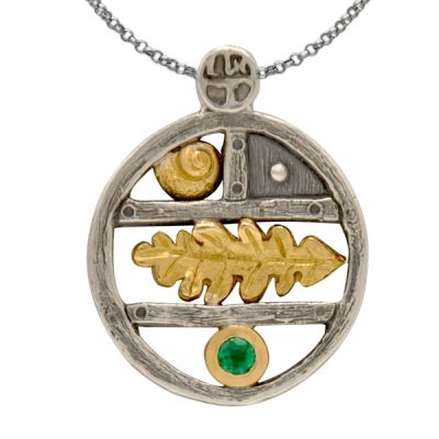 Pendentif en argent, rond en forme d'étagère sur laquelle sont disposés des motifs en or coquillage et feuille ainsi qu'une emeraude